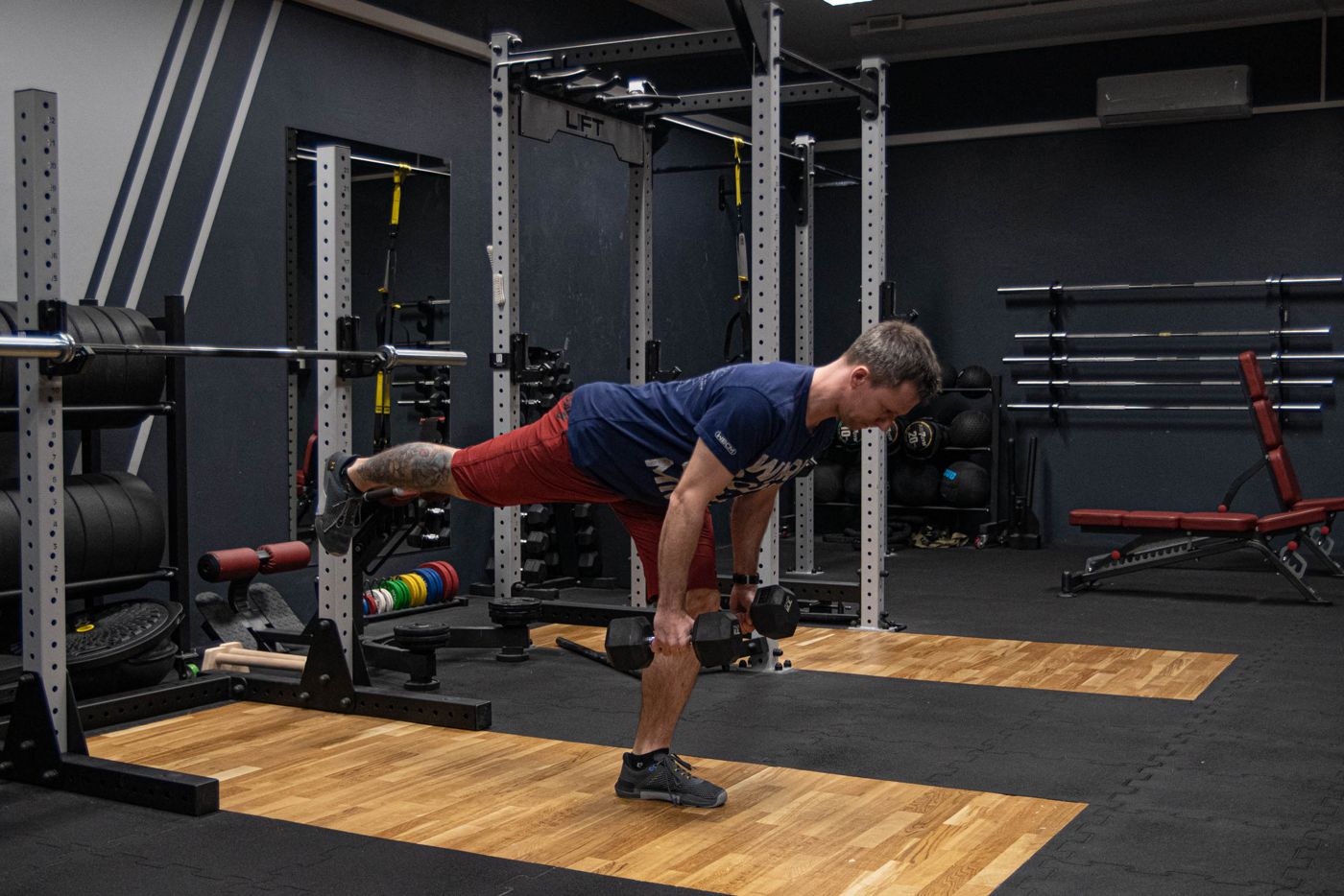 Dorian Rochowski w martwym ciągu na jednej nodze z hantlami w studiu Lift S&C